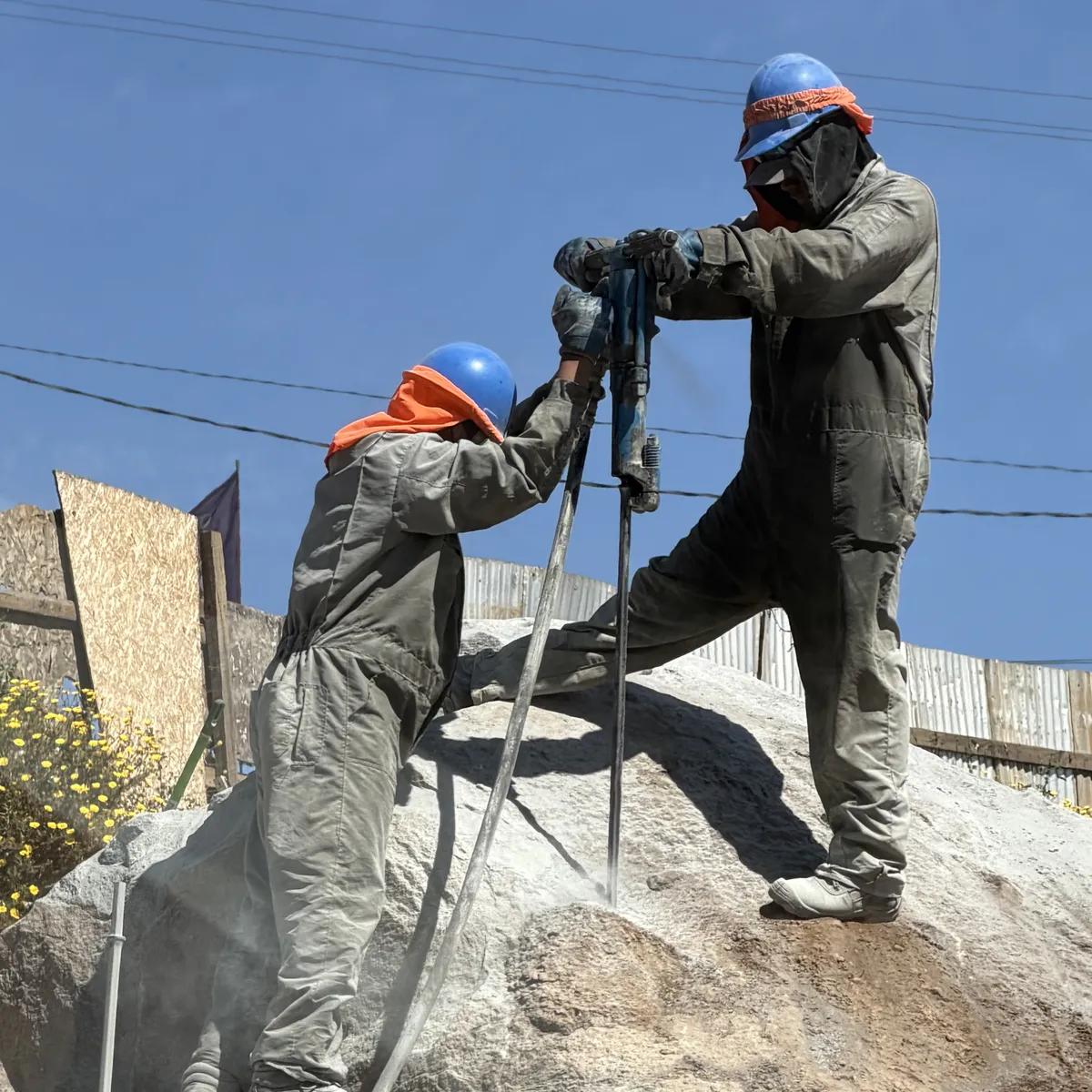 Operador realizando perforación de roca con maquinaria especializada en una pendiente pronunciada